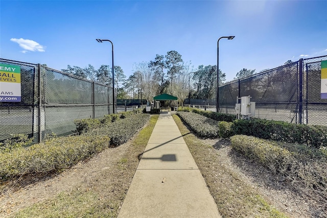 view of property's community featuring a tennis court, a gate, and fence