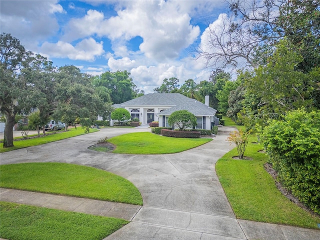 view of front of house with a chimney, concrete driveway, and a front lawn