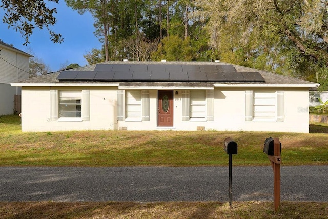 view of front of home with solar panels and a front yard