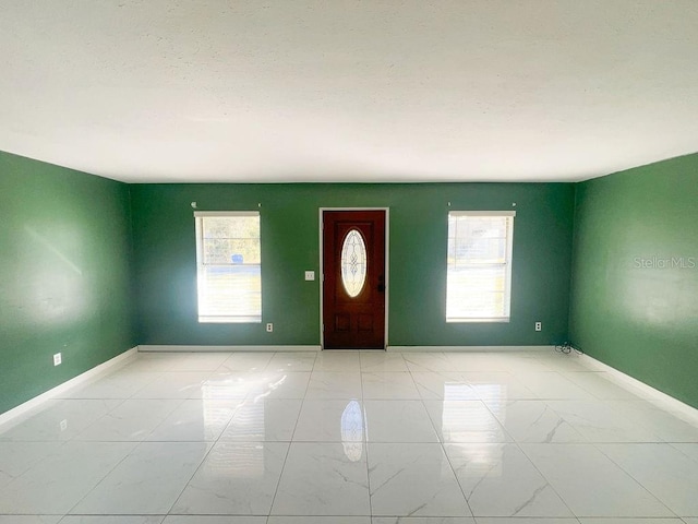 foyer with baseboards and marble finish floor