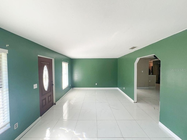 entrance foyer featuring baseboards, arched walkways, and marble finish floor