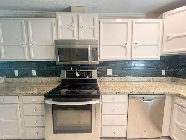 kitchen featuring tasteful backsplash, white cabinets, stainless steel appliances, and light stone counters