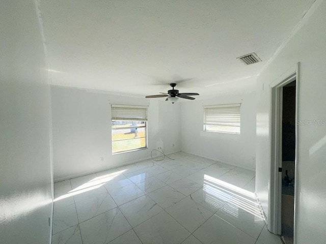 spare room with a ceiling fan, visible vents, and marble finish floor