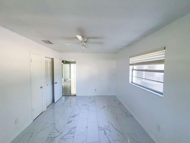 empty room with visible vents, marble finish floor, a ceiling fan, and baseboards