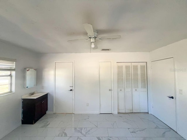 unfurnished bedroom featuring a sink, visible vents, marble finish floor, and ceiling fan