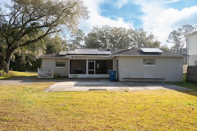 back of property with solar panels, a lawn, fence, and a sunroom