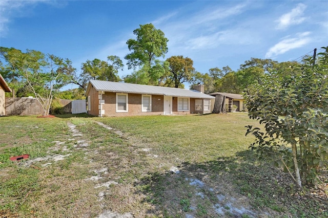 view of front of property featuring a chimney, metal roof, a front yard, and fence