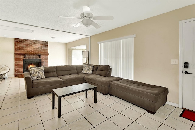 living room with light tile patterned floors, a fireplace, a textured ceiling, and a ceiling fan