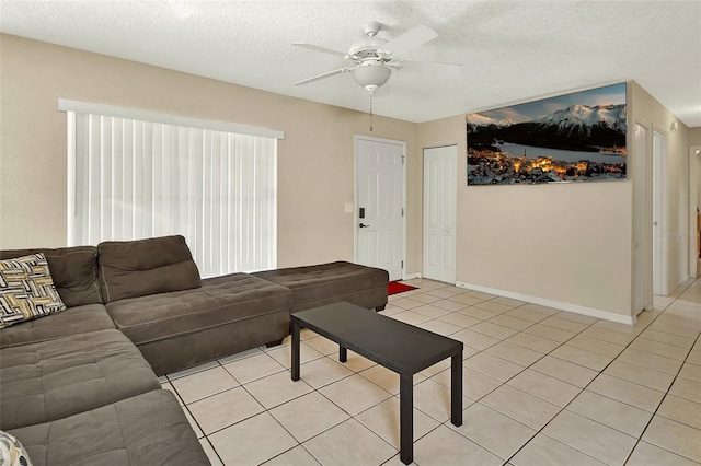 living area with light tile patterned floors, baseboards, a textured ceiling, and a ceiling fan