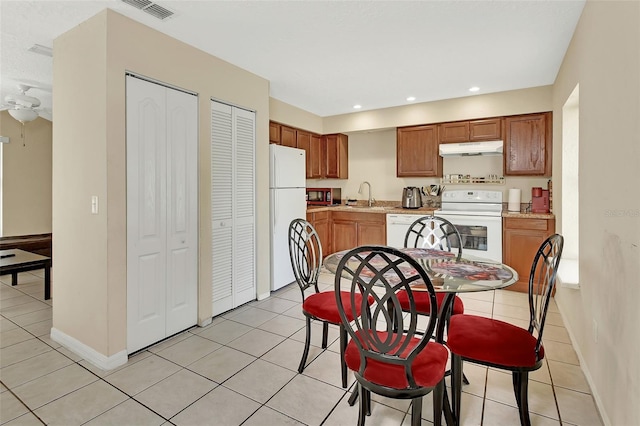 kitchen with visible vents, under cabinet range hood, light countertops, white appliances, and a sink