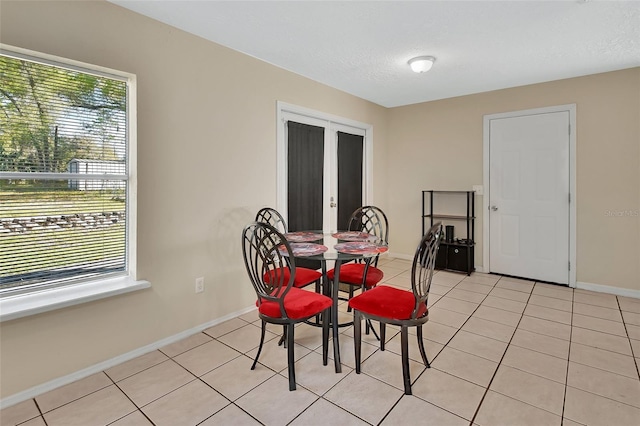 dining area with light tile patterned flooring, a healthy amount of sunlight, baseboards, and a textured ceiling