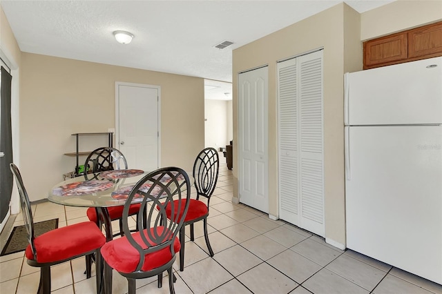 dining space with light tile patterned floors, visible vents, and a textured ceiling