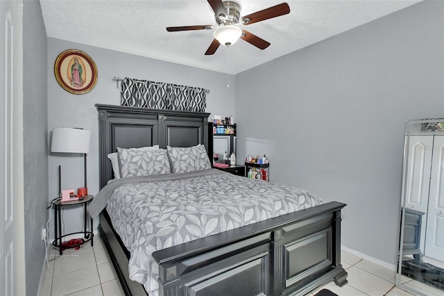 bedroom with light tile patterned flooring, a textured ceiling, baseboards, and a ceiling fan