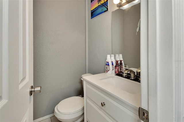 bathroom featuring toilet, vanity, and a textured wall