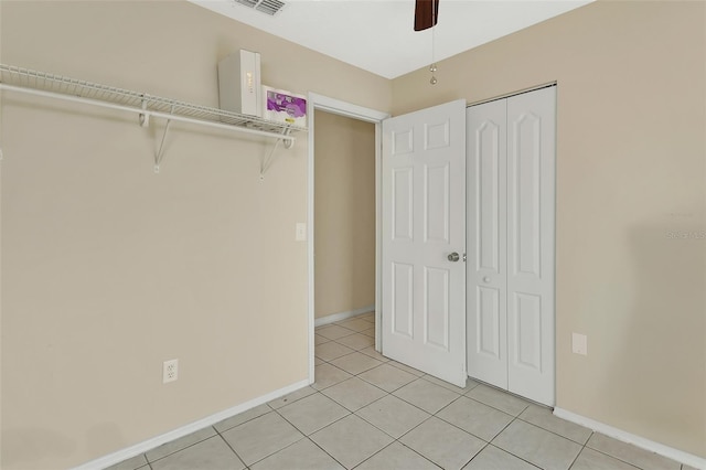 unfurnished bedroom with light tile patterned floors, a closet, baseboards, and ceiling fan