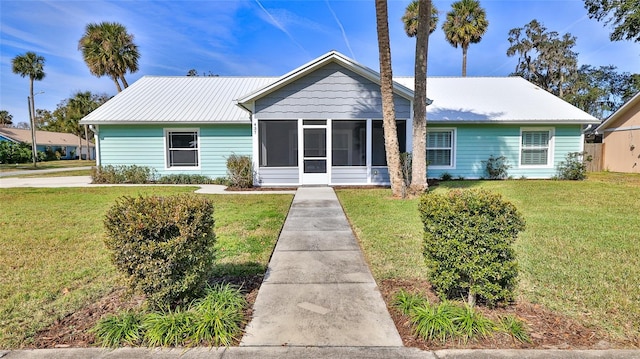 view of front of property featuring metal roof, a front yard, and a sunroom