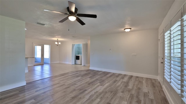 empty room with visible vents, washer / dryer, light wood-type flooring, and baseboards