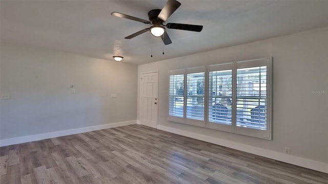 empty room with baseboards, wood finished floors, and a ceiling fan