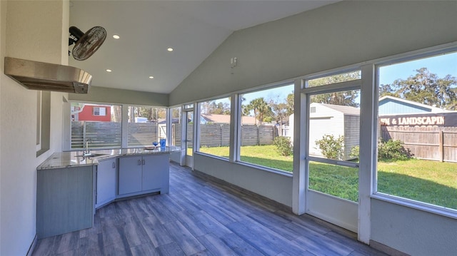 unfurnished sunroom featuring a sink, plenty of natural light, and lofted ceiling