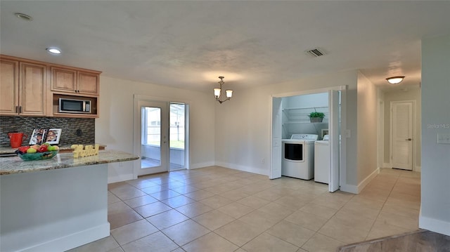 kitchen featuring stainless steel microwave, backsplash, visible vents, light tile patterned flooring, and separate washer and dryer