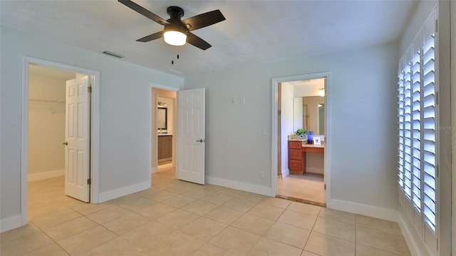 unfurnished bedroom with a spacious closet, visible vents, baseboards, light tile patterned floors, and a closet