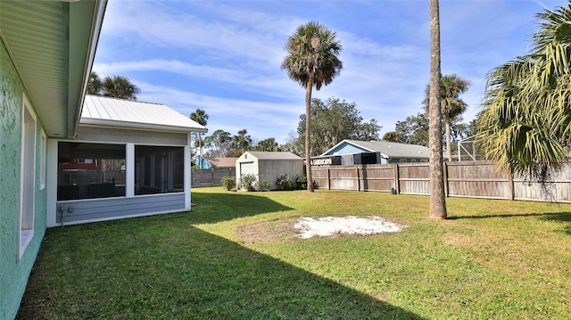 view of yard featuring a storage unit, an outbuilding, a fenced backyard, and a sunroom