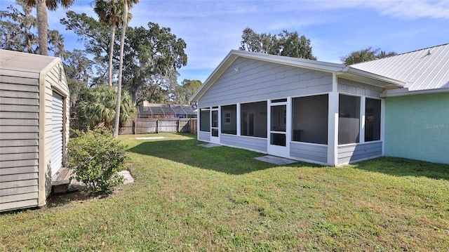 view of yard featuring a sunroom, an outdoor structure, and fence