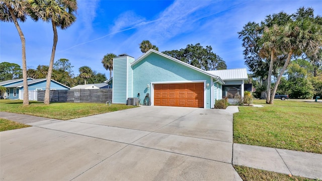 view of front of property with a front yard, fence, driveway, an attached garage, and metal roof