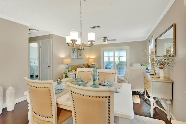 dining room featuring visible vents, dark wood-type flooring, ceiling fan with notable chandelier, crown molding, and baseboards