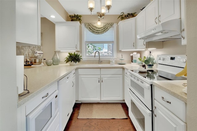 kitchen featuring under cabinet range hood, light countertops, white appliances, white cabinetry, and a sink