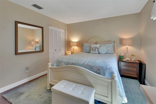 bedroom featuring a closet, visible vents, baseboards, and wood finished floors