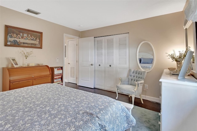 bedroom with wood finished floors, baseboards, visible vents, and a closet