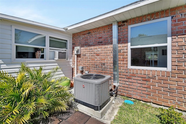 details featuring central AC unit, brick siding, and electric meter