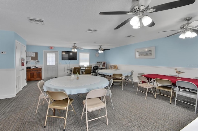 dining area featuring carpet flooring, visible vents, and a textured ceiling