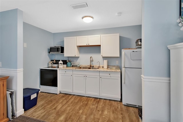 kitchen with electric range, visible vents, a sink, stainless steel microwave, and freestanding refrigerator