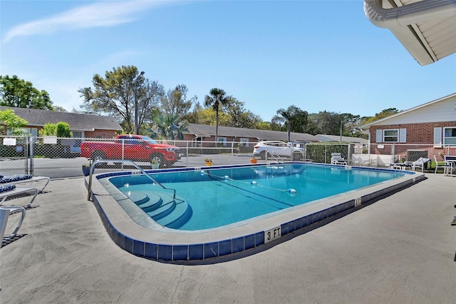 community pool with a patio area and fence