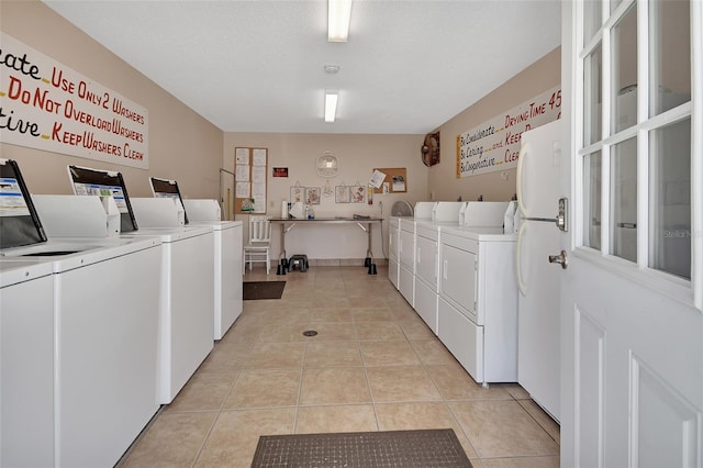 community laundry room featuring washer and dryer and light tile patterned floors