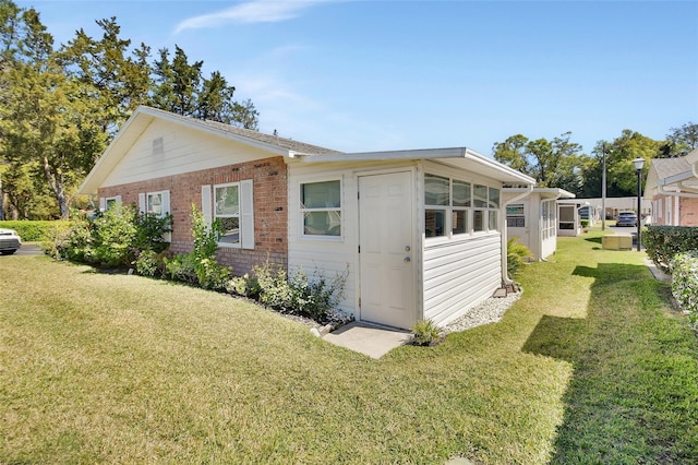 view of side of home featuring brick siding and a yard