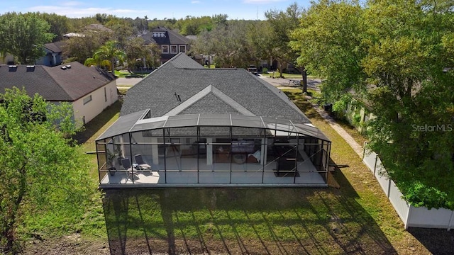 rear view of house featuring glass enclosure, an outdoor pool, roof with shingles, and fence