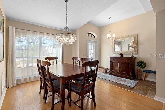 dining room with baseboards, an inviting chandelier, a textured ceiling, and light wood-style floors