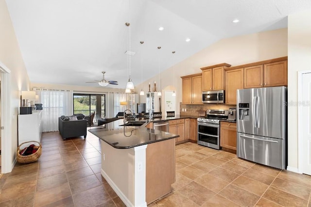 kitchen with a sink, open floor plan, appliances with stainless steel finishes, dark countertops, and tasteful backsplash