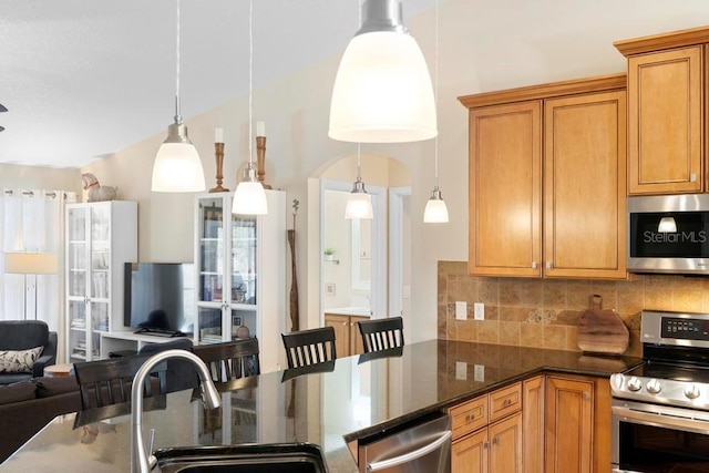 kitchen featuring a sink, tasteful backsplash, open floor plan, stainless steel appliances, and dark stone counters