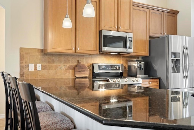 kitchen featuring a breakfast bar, hanging light fixtures, backsplash, and stainless steel appliances