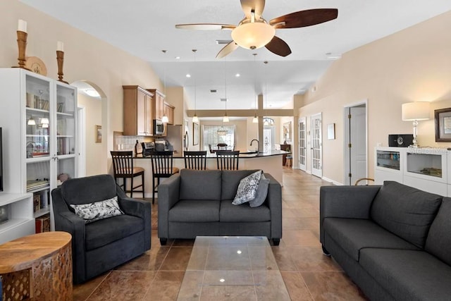 tiled living room with a ceiling fan, a sink, french doors, arched walkways, and lofted ceiling