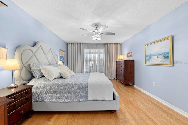 bedroom with baseboards, light wood-style floors, a ceiling fan, and a textured ceiling