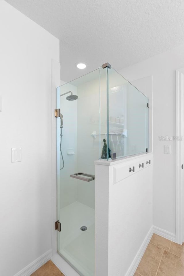 full bathroom with baseboards, a shower with shower door, and a textured ceiling