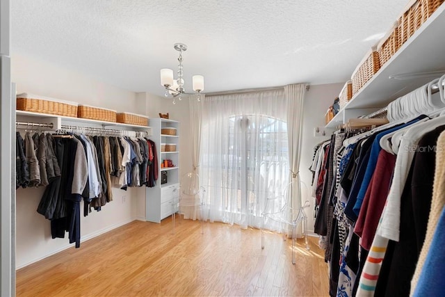 spacious closet featuring an inviting chandelier and wood finished floors