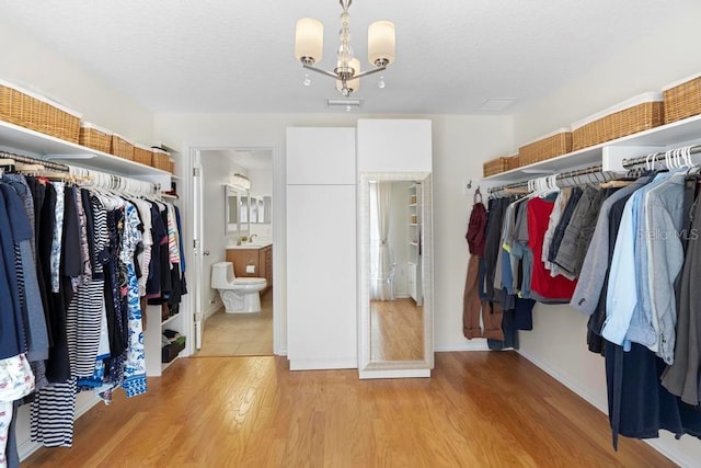 walk in closet featuring a notable chandelier, visible vents, light wood-type flooring, and a sink