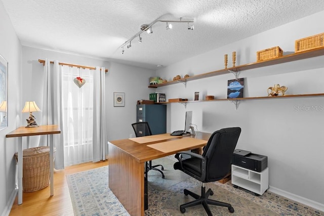 office area with rail lighting, baseboards, light wood-type flooring, and a textured ceiling