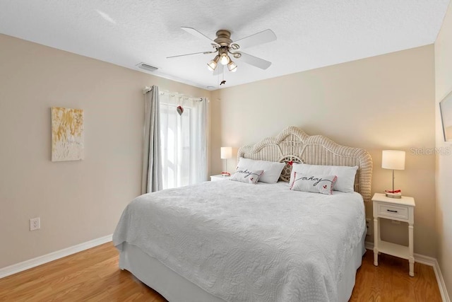 bedroom with light wood-type flooring, visible vents, baseboards, and ceiling fan